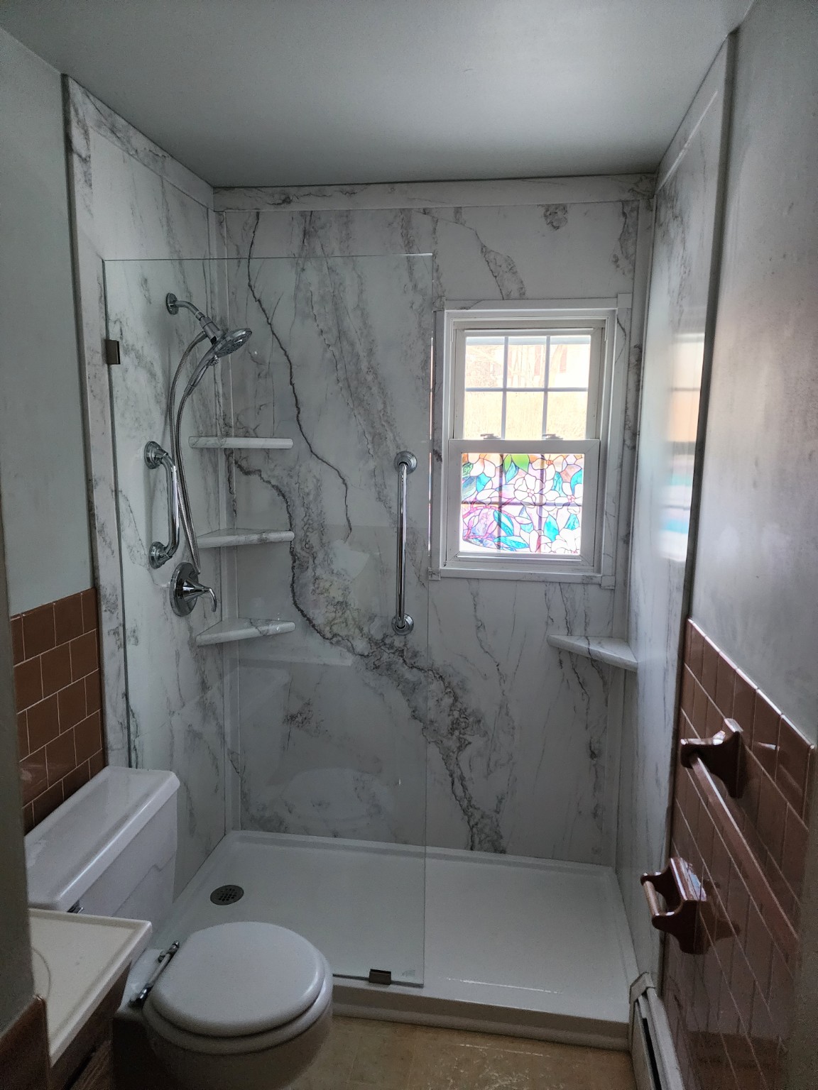 Marble-look acrylic shower with window, glass panel, corner shelves and grab bars