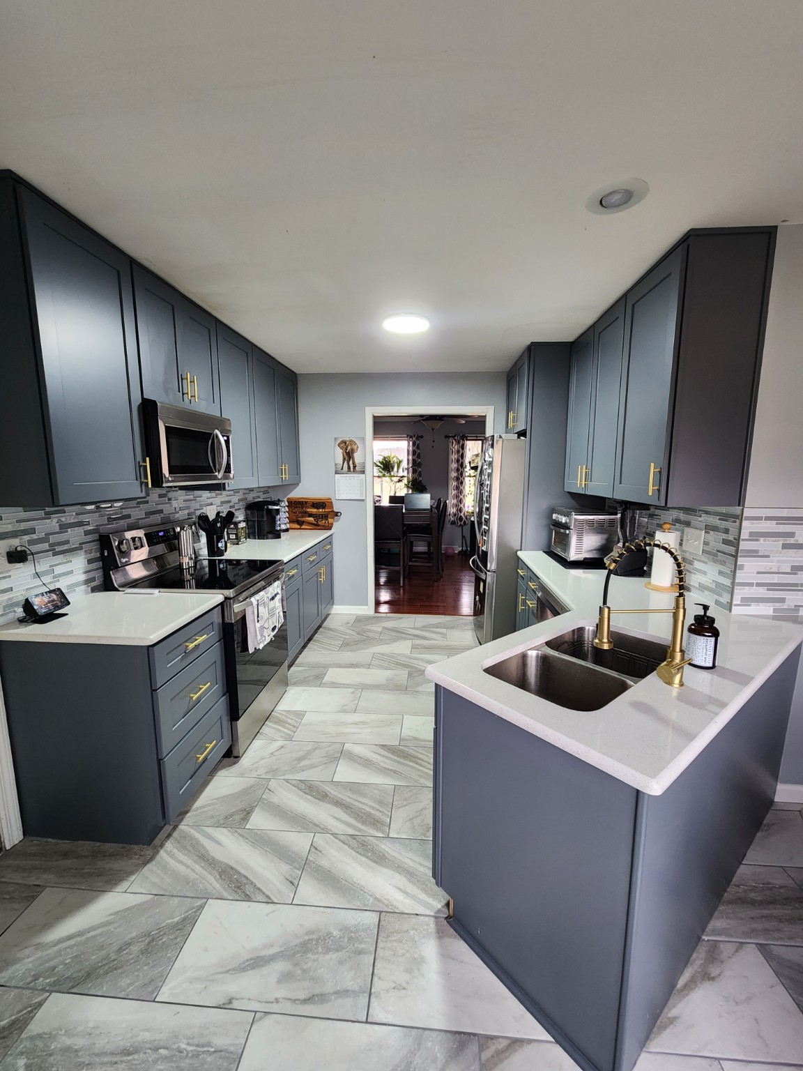Kitchen renovation with gray cabinets, light countertops and gold fixtures