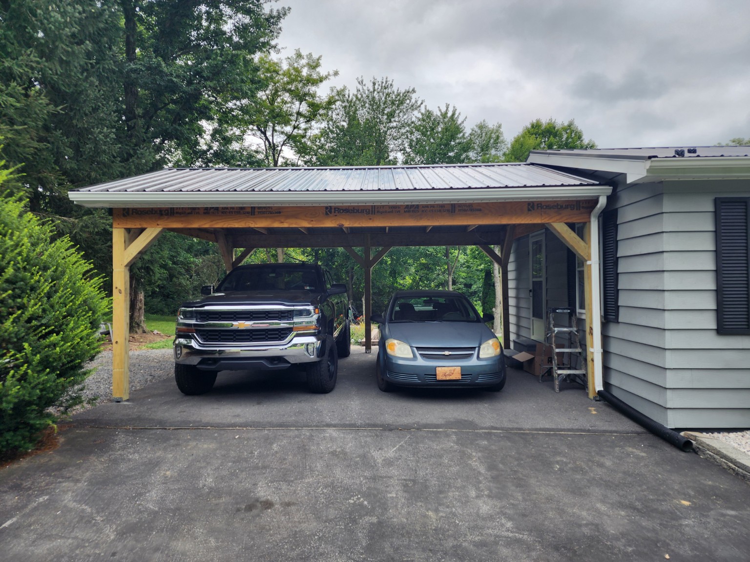 New timber-framed carport with metal roof beside a home
