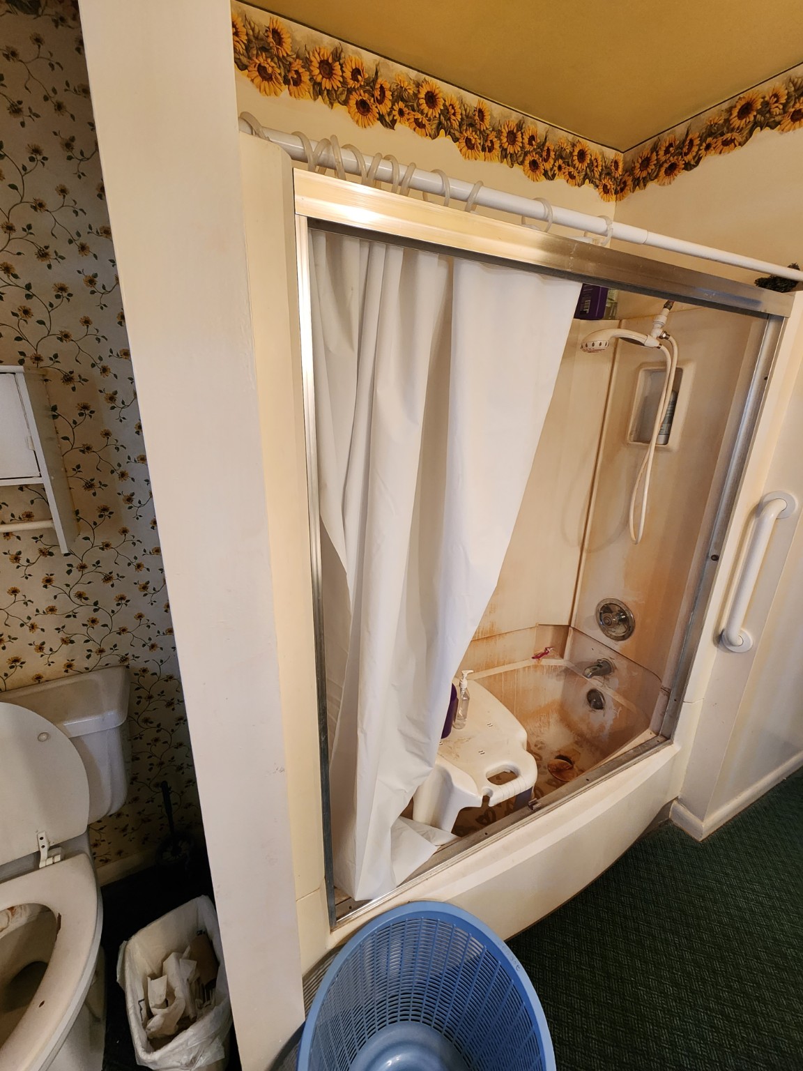 Before: Older bathtub enclosure with floral wallpaper