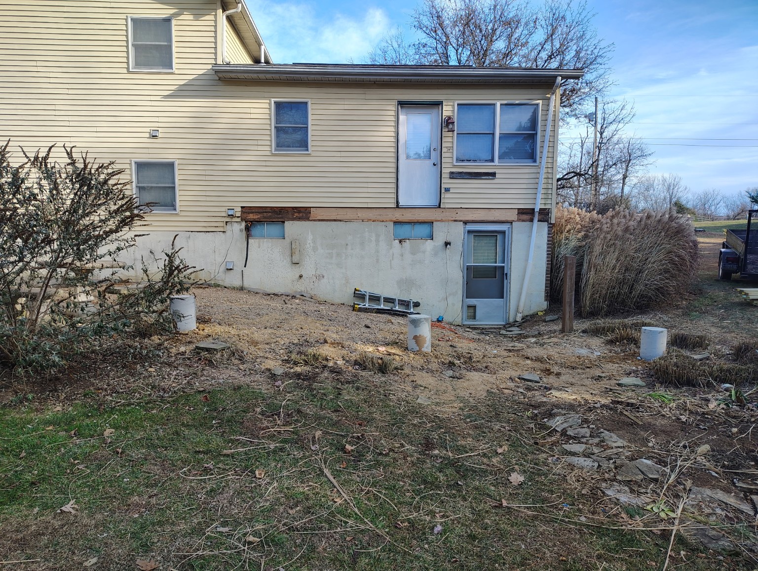 Before: house exterior and cleared area before covered porch construction