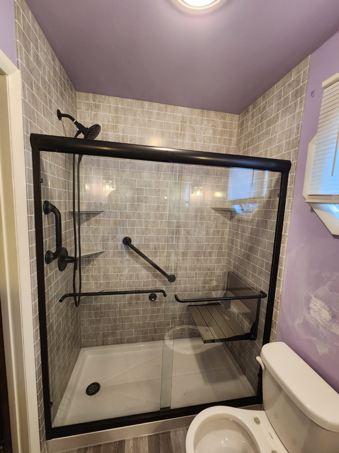 After: Shower transformation with black fixtures and folding seat