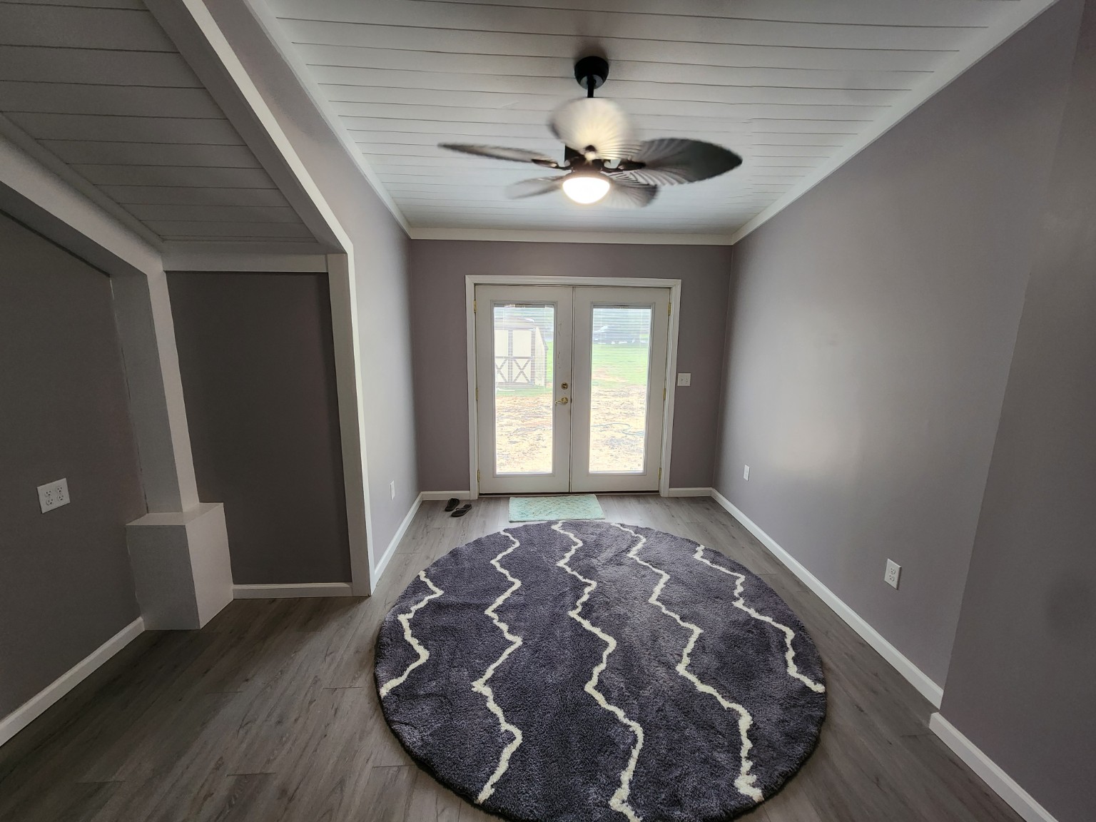 Finished sunroom interior with new flooring, painted walls, white ceiling and double doors